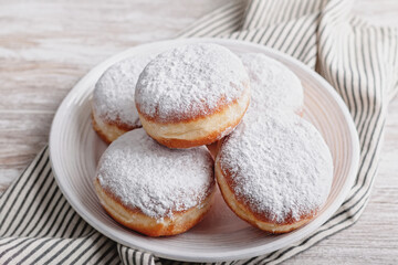 Delicious strawberry jam filled berliner doughnuts on white plate with napkin on wooden table top...