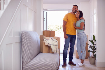 Excited Couple With Boxes Standing n Hallway Of New Home On Moving Day
