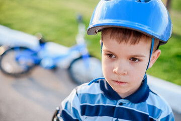 Fototapeta na wymiar Cute child in helmet and protection stands near his bike