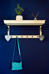 Blue leather handbag hanging on wooden clothes hanger