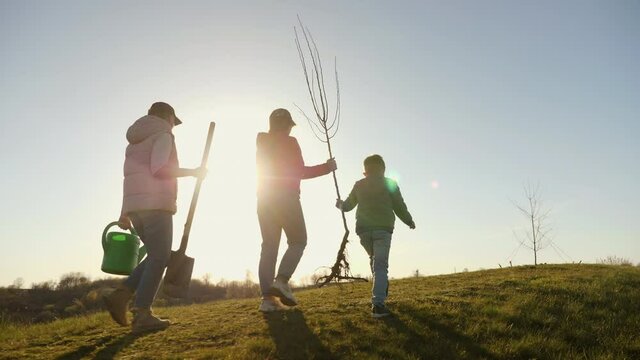 Mom with two children going to plant a tree