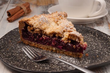 shortbread cherry pie on a dark plate with a Cup of tea