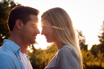 Portrait Of Loving Couple In Countryside Against Flaring Sun