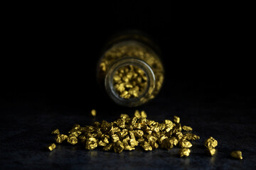 Gold stones in the darkness, on a dark background, slept from the bottle, yellow stones, gold, in close-up, still life