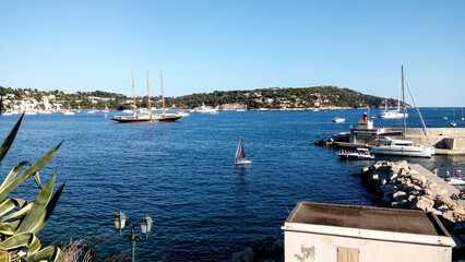 Obraz premium Yachts and boats in the harbor. Beautiful panoramic landscape of Villefranche-sur-mer on a sunny day. A wonderful trip to the Cote d'Azur in France. Scenic harbour view of the city of the sea country.