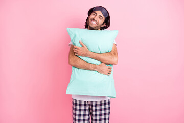 Photo of young happy smiling handsome man hug embrace pillow just woke up isolated on pink color...