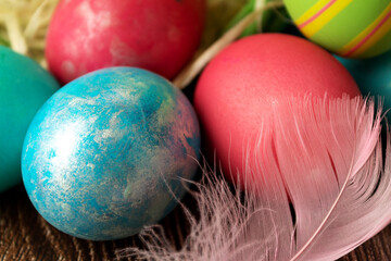 Colored Easter eggs with a feather on the table, in a close-up