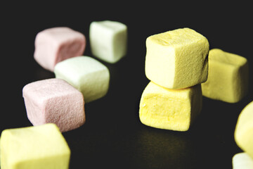 Scattered yellow marshmallows, on a dark background, close-up, still life