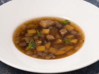 porcini mushroom soup with potatoes and onions on a white plate