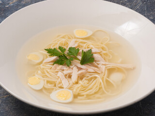 Chicken soup with homemade noodles on a white plate in a restaurant