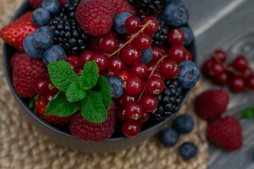 Ripe sweet different berries in bowl on wooden table. Harvest Concept.