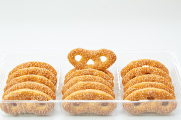 Sweet pretzels, cookies in a plastic transparent box on a white background, in a close-up,...