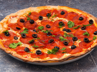 pepperoni pizza with olives and mozzarella cheese, decorated with greens