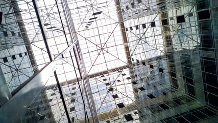 The glass dome of the office building and the mirrored facade reflecting the sky and elements of the structure of the building,View from inside the building.