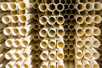 A stack of white electrical PVC conduit pipes in rows end on giving a repeat pattern of circles.