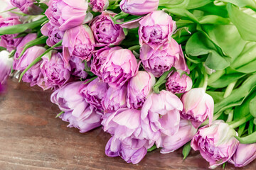 large bouquet of beautiful pink tulips on a wooden background lie in a diagonal composition