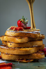 Stack of french toasts with fresh strawberries, raspberries, maple syrup, and powdered sugar. Halva spread drizzle on top. Tasty morning breakfast or brunch with gluten free bread. Easy and healthy.