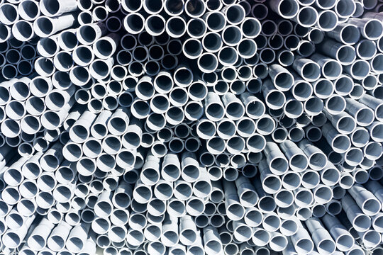 A Stack Of White Electrical PVC Conduit Pipes In Rows End On Giving A Repeat Pattern Of Circles.