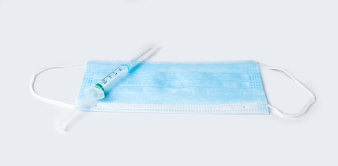 Medical mask and syringe on a white background. Isolate. Vaccination, immunization, treatment to Covid-19. Close-up. Copy space.