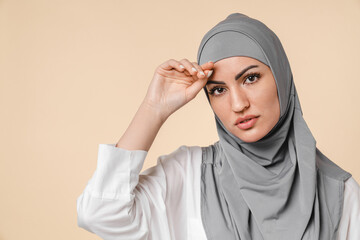 Tired exhausted young arabian muslim Middle eastern islamic girl woman in grey hijab isolated on beige background. Tedious work, bored, sad, feeling bad, headache, emotional stress concept