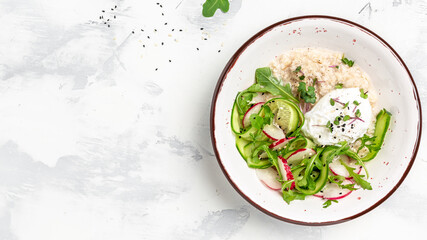 Breakfast oatmeal porridge with poached egg with vegetable salad of radish, cucumbers, arugula and microgreens. Healthy balanced food. banner, menu recipe place for text, top view