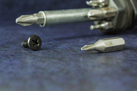 Screwdriver with bits in close-up on a dark blue background