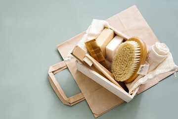 Natural bathroom accessories: wooden toothbrushes, bamboo comb, organic soap, reusable cotton bags on a green background. Zero waste shopping, eco-friendly lifestyle.