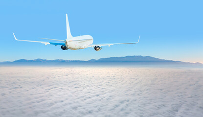 Fototapeta na wymiar White passenger airplane over the clouds - Travel by air transport