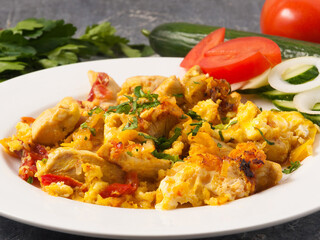 egg scramble with chicken decorated with greens on a white plate