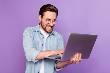 Photo of unhappy angry young man look hold laptop write letter work isolated on purple color background - obrazy, fototapety, plakaty