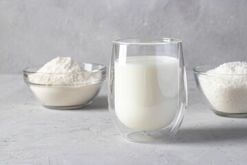 Coconut products: coconut flakes, milk and flour in a transparent dish on light gray background. Healthy eating