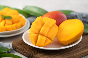 Diced fresh mango fruit on a white plate with leaves.