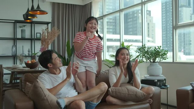 Happy asian family dancing together on sofa in the living room at home.