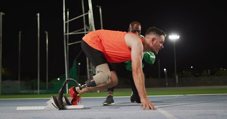 Diverse male coach and disabled male athlete with running blade ready to start a run - Powered by Adobe