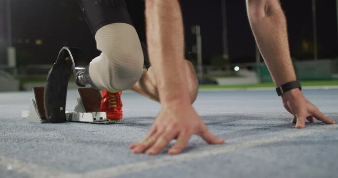 Low section of caucasian disabled male athlete with running blade getting ready to start a run