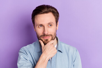 Photo of funny clever young guy wear denim clothes arm chim smiling looking empty space isolated purple color background