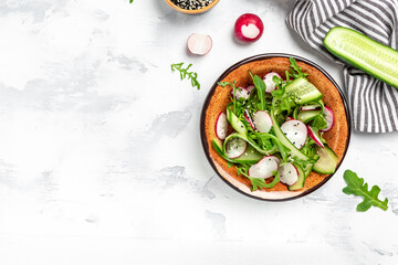 Green vegan salad from green leaves mix and vegetables. salad of radish, cucumbers, arugula. Healthy vegan food. place for text, top view