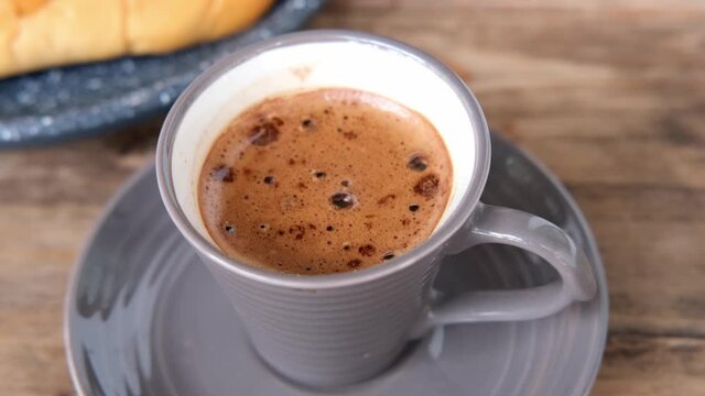 Cappuccino coffee in gray cup and saucer on an old wooden table, ruddy fresh croissants, concept fresh pastries, morning coffee, caffeine addiction, energy boost