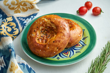 Classic turkish bread tortilla with sesame seeds in a patterned plate on a white tablecloth. Close up view on ramazan pidesi