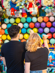 Pareja joven jugando en una tómbola de dardos explotando globos