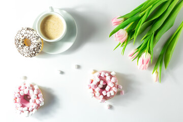 Fototapeta na wymiar Flatley with cappuccino and donuts with marshmallows, on a white background, pink tulips top view, isolated