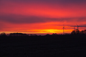 Dramatischer Sonnenaufgang mit Windrädern.