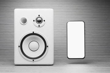 A mockup of a smartphone with a white screen near a white music speaker. White screen of a smartphone for your design of a music application or advertisement on a background of white music speakers. 
