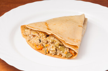crepes with minced meat and vegetables on a white plate