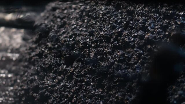 Close-up of fresh asphalt mix. An asphalt paver is laying asphalt mix on the road. Repair of roads at night, construction of new roads.