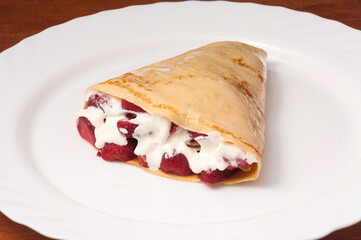 crepe with strawberries and cream on a white plate