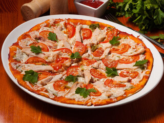 pizza Caesar on a white plate on a wooden table with tomato sauce