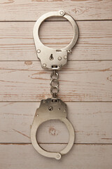 Closed handcuffs lie on a wooden background. Top view. The concept of punishment for treason