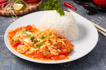 Chinese omelet with tomatoes and rice on a white plate