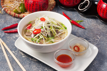 Vietnamese Pho Bo with rice noodles and beef on a grey background
